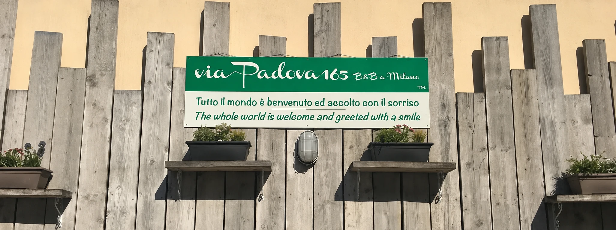 Il cartello di Via Padova 165: Tutto il mondo è benvenuto ed accolto con il sorriso